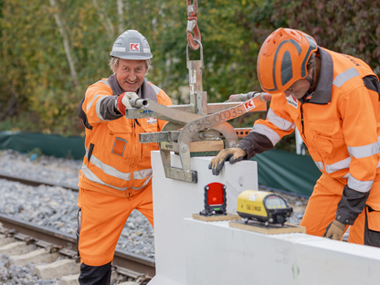 KASSECKER Mitarbeiter Albert KASSECKER Vorarbeiter im Bahn- und Ingenieurbau bei Arbeiten am Gleis. Er trägt orange Arbeitskleidung und einen grauen Helm mit KASSECKER Logo.
