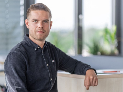 KASSECKER Mitarbeiter Thomas Ein KASSECKER Mitarbeiter in einer Büroumgebung blickt in die Kamera. Er trägt ein dunkles Hemd.