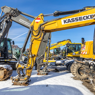KASSECKER Bagger Gelbe KASSECKER Bagger, die auf einer Baustelle geparkt sind, mit klarem blauem Himmel im Hintergrund.