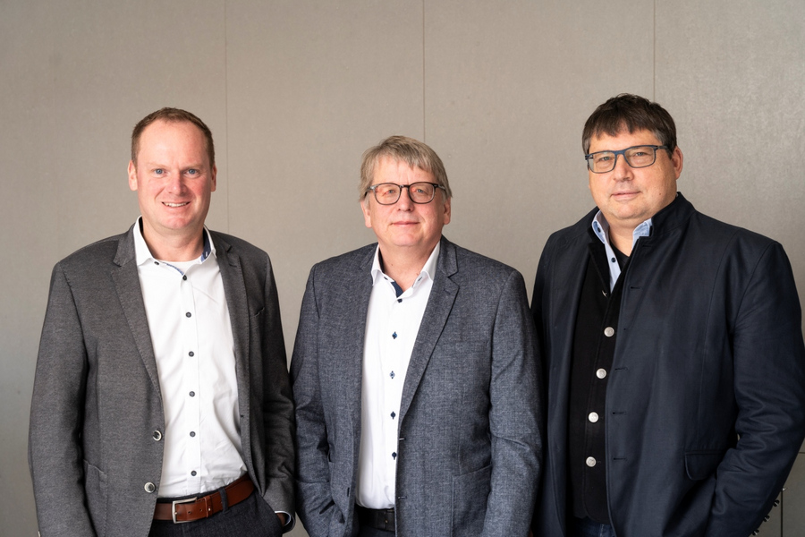 Drei Geschäftsführer des Bauunternehmens Kassecker vor einer Betonwand.