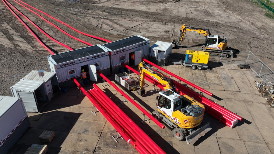 Luftaufnahme einer Baustelle der Franz KASSECKER GmbH mit mehreren roten Rohren, zwei Baggern und mehreren Containern auf einem mit Stahlplatten ausgelegten Erdboden